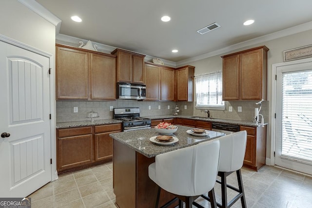 kitchen featuring stainless steel appliances, sink, stone countertops, a center island, and a breakfast bar area