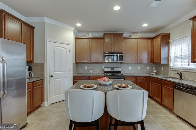 kitchen featuring a center island, sink, decorative backsplash, stone countertops, and stainless steel appliances