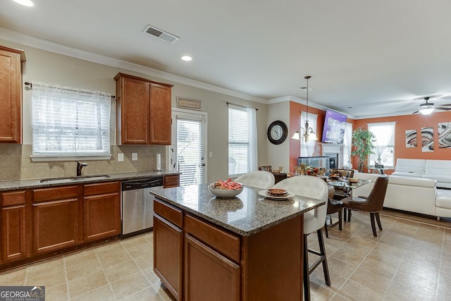 kitchen featuring sink, stainless steel dishwasher, ceiling fan, decorative light fixtures, and a kitchen island