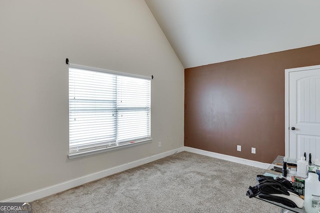 carpeted spare room featuring high vaulted ceiling