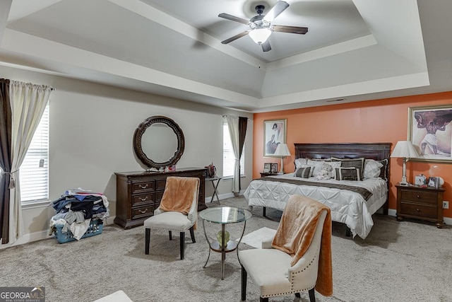 bedroom featuring light carpet, a tray ceiling, and ceiling fan