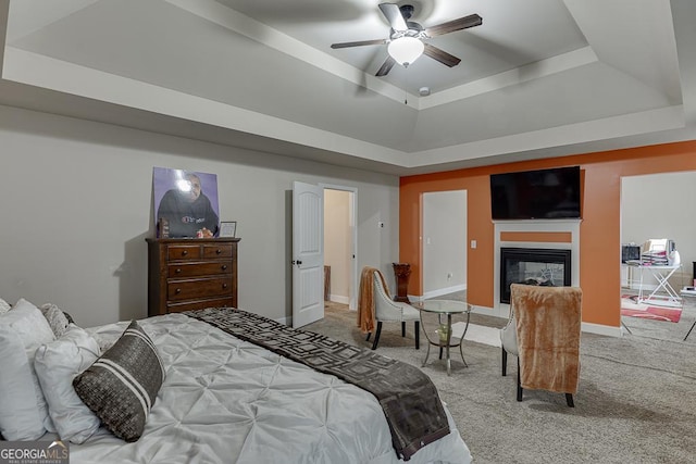 carpeted bedroom featuring ceiling fan and a tray ceiling