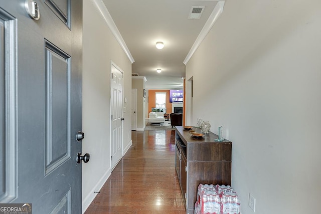 hallway with dark wood-type flooring and ornamental molding