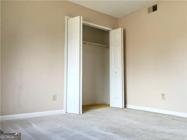 unfurnished bedroom featuring a closet and light colored carpet