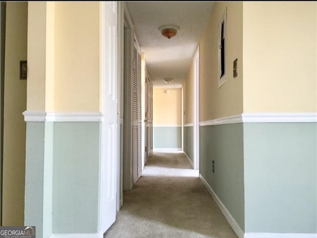 hallway with light carpet and a textured ceiling