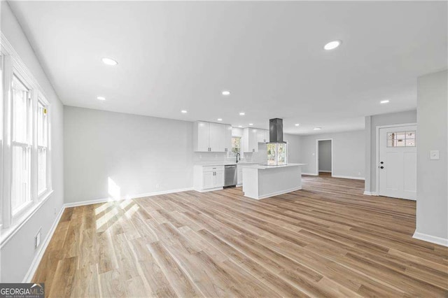 unfurnished living room featuring plenty of natural light and light hardwood / wood-style flooring