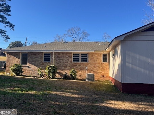 rear view of house featuring a lawn and central air condition unit