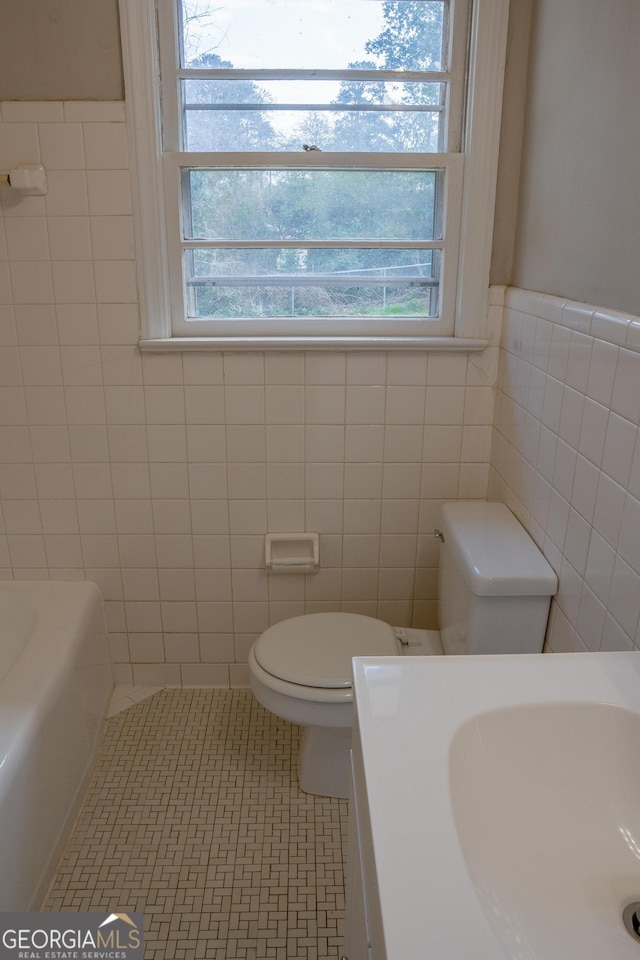 bathroom featuring sink, a wealth of natural light, tile walls, and toilet