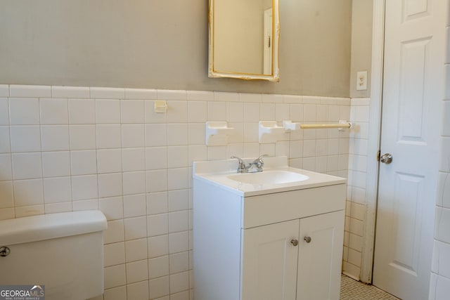 bathroom with vanity, toilet, and tile walls