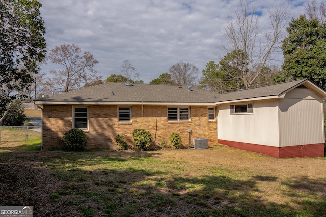 rear view of property featuring cooling unit and a lawn