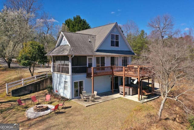 rear view of property with a sunroom, a jacuzzi, a patio, a deck, and an outdoor fire pit