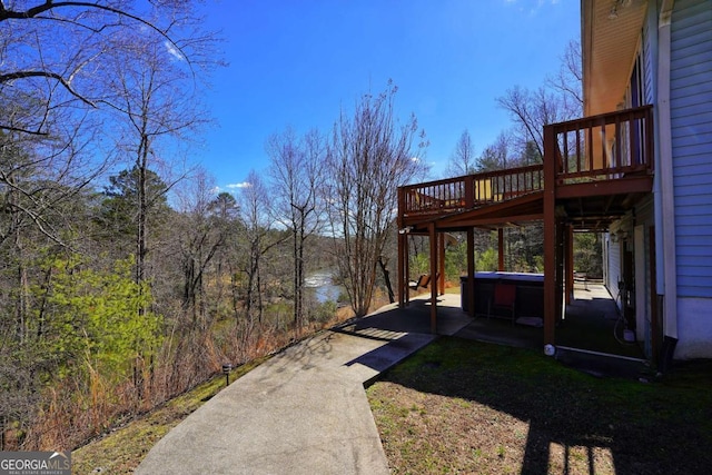 view of yard with a deck with water view and a hot tub