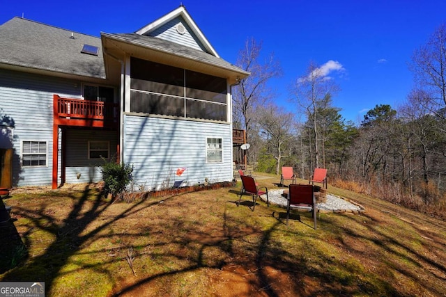 view of property exterior featuring a lawn, a sunroom, and an outdoor fire pit