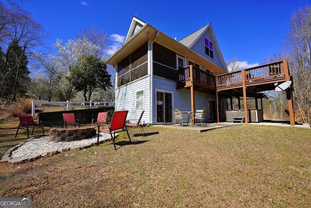 rear view of house featuring a fire pit, a sunroom, a patio, a hot tub, and a lawn