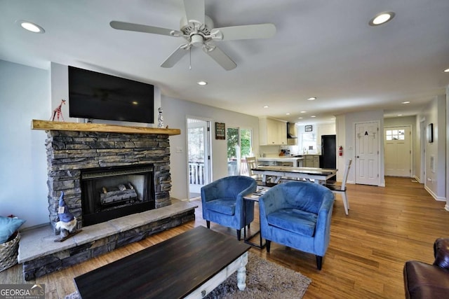 living room with ceiling fan, a fireplace, and light hardwood / wood-style floors