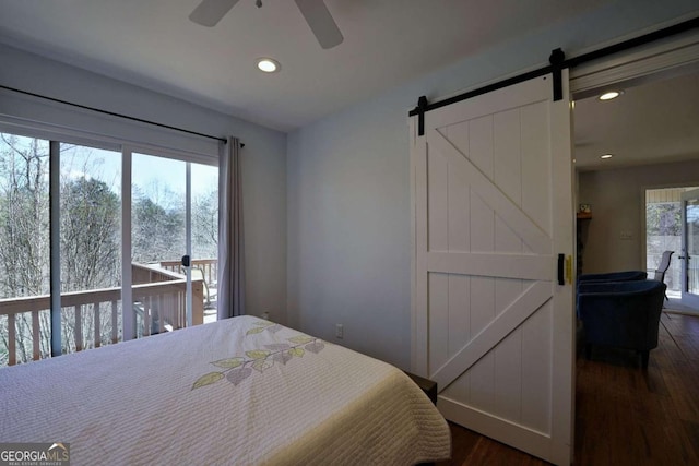 bedroom featuring ceiling fan, a barn door, and dark wood-type flooring