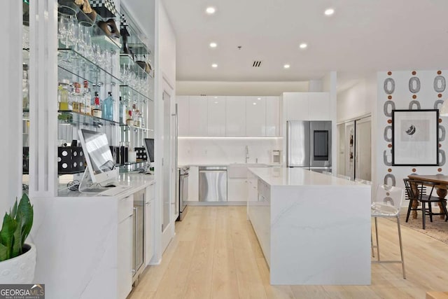 kitchen featuring white cabinetry, stainless steel appliances, light hardwood / wood-style floors, a kitchen bar, and a kitchen island