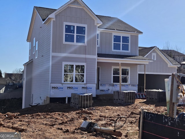 view of front of home with board and batten siding, cooling unit, covered porch, and roof with shingles