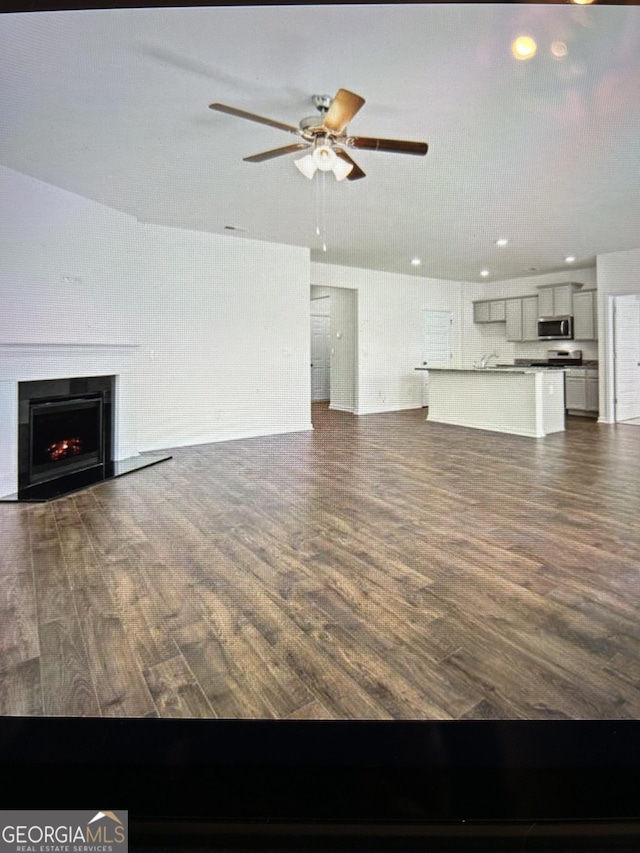 unfurnished living room featuring ceiling fan and dark hardwood / wood-style flooring