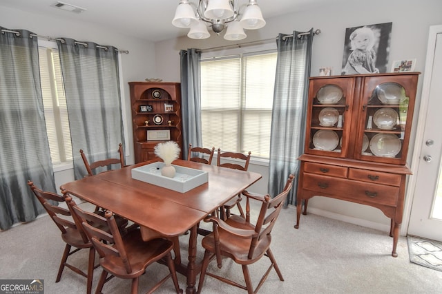 carpeted dining area featuring an inviting chandelier