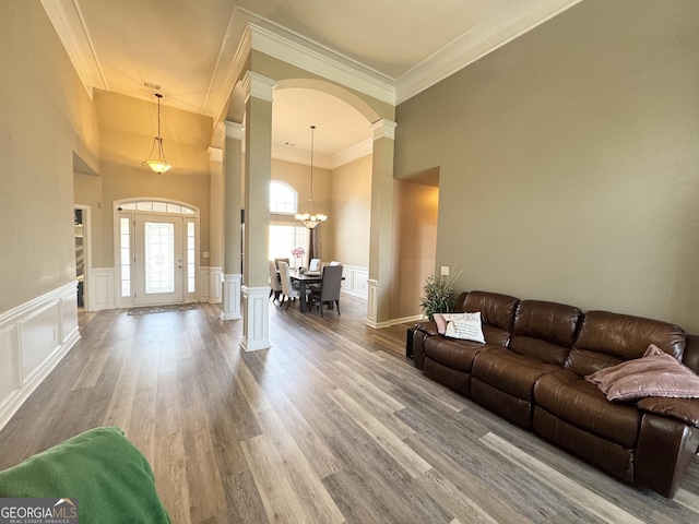 interior space featuring ornate columns, crown molding, a chandelier, and wood-type flooring