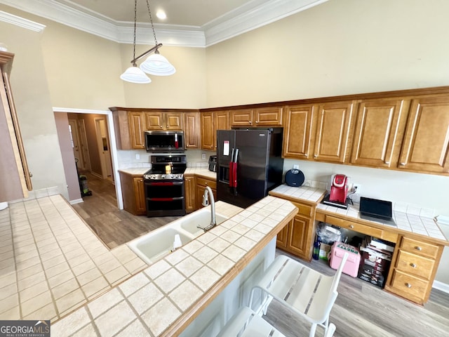 kitchen with hanging light fixtures, stainless steel appliances, tile counters, and sink