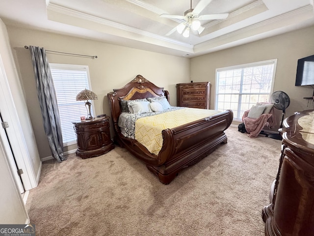 carpeted bedroom featuring crown molding, ceiling fan, and a raised ceiling