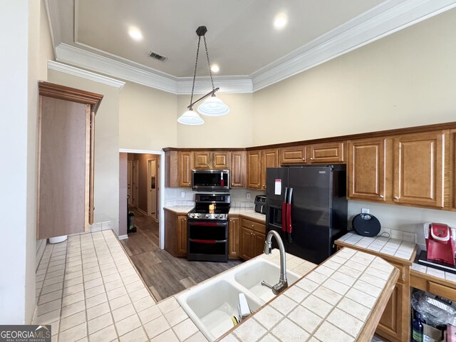 interior space with pendant lighting, tile countertops, a fireplace, a notable chandelier, and crown molding