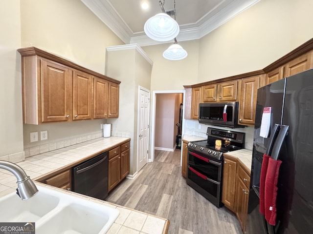 kitchen featuring tile counters, sink, crown molding, and stainless steel appliances