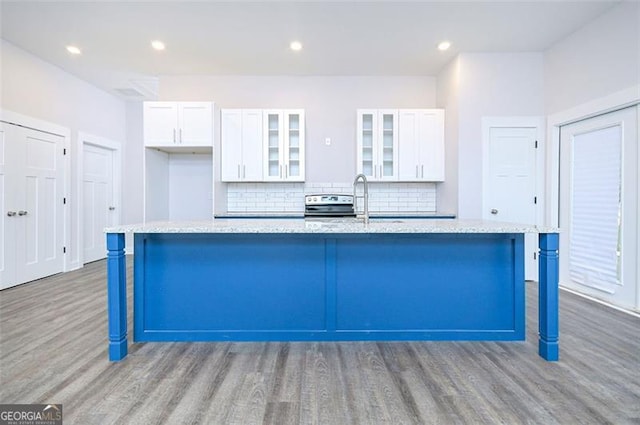 kitchen featuring backsplash, a kitchen bar, a center island with sink, and white cabinets