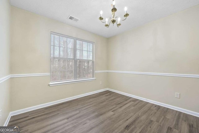 empty room with a chandelier and hardwood / wood-style floors