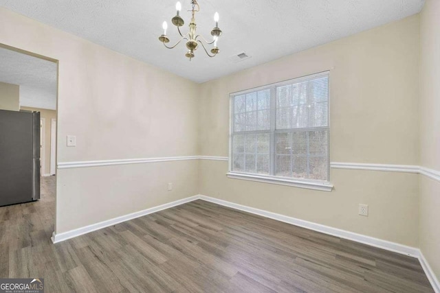 unfurnished dining area featuring a chandelier, hardwood / wood-style floors, and a textured ceiling