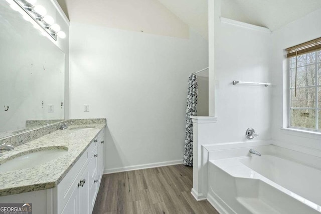 bathroom with hardwood / wood-style flooring, plenty of natural light, a bathtub, and lofted ceiling