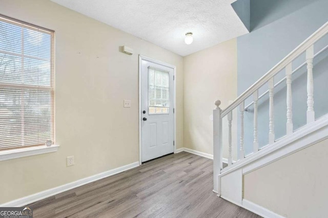 entryway with a textured ceiling and light hardwood / wood-style flooring