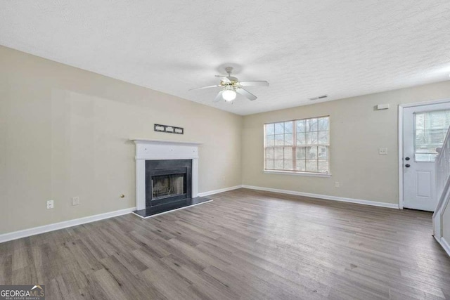 unfurnished living room featuring ceiling fan, plenty of natural light, a textured ceiling, and hardwood / wood-style flooring