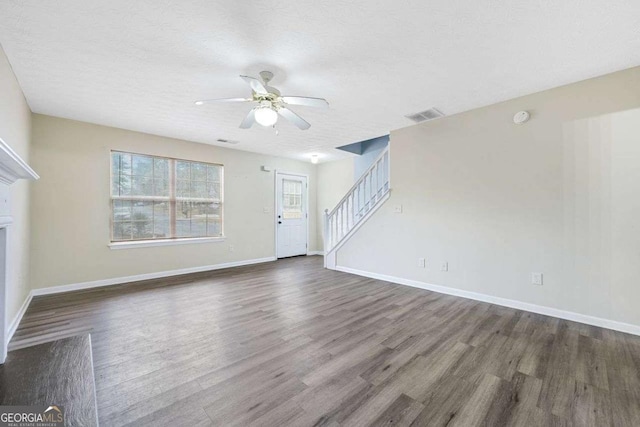 unfurnished living room featuring ceiling fan, dark hardwood / wood-style flooring, and a textured ceiling