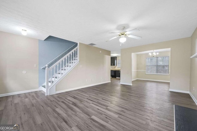 unfurnished living room with hardwood / wood-style floors, ceiling fan with notable chandelier, and a textured ceiling