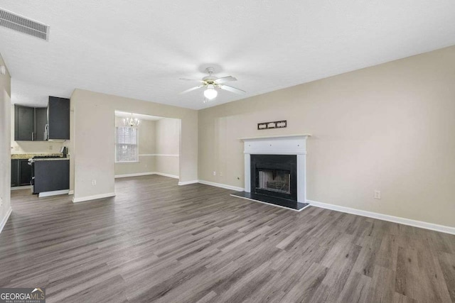 unfurnished living room featuring dark hardwood / wood-style flooring, ceiling fan with notable chandelier, and a textured ceiling