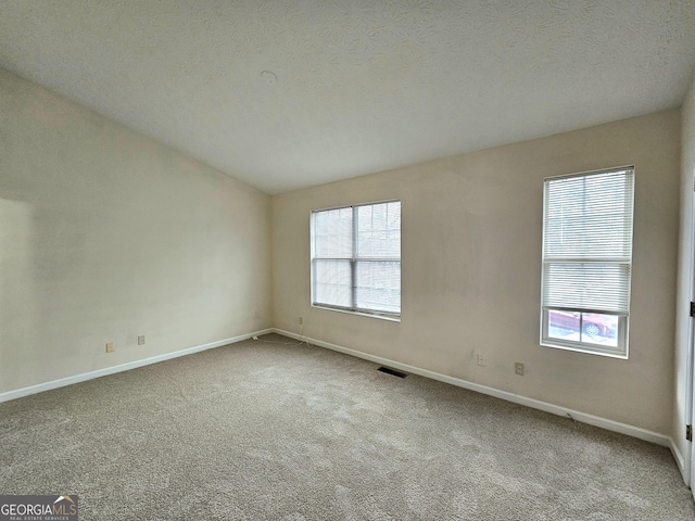 carpeted spare room with a textured ceiling