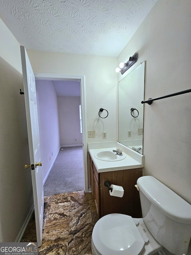 bathroom featuring vanity, a textured ceiling, and toilet