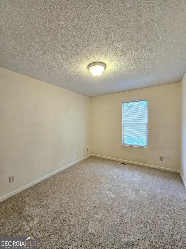 unfurnished room with carpet flooring and a textured ceiling