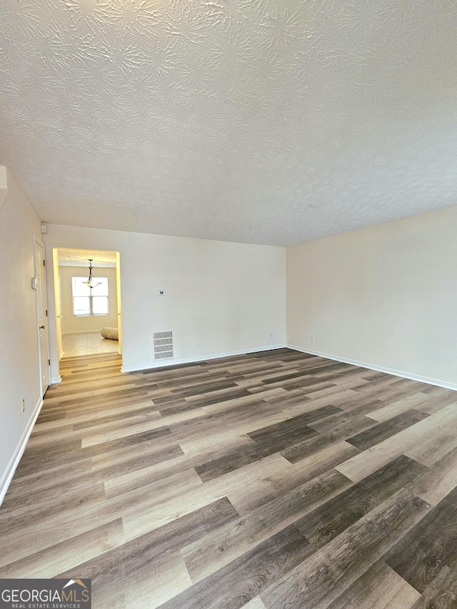 spare room with hardwood / wood-style flooring and a textured ceiling