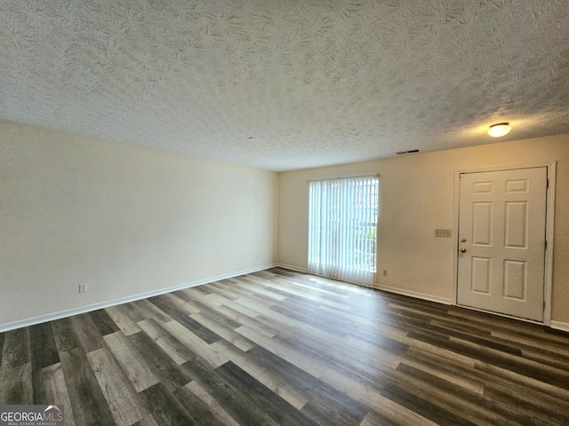 spare room with a textured ceiling and dark wood-type flooring