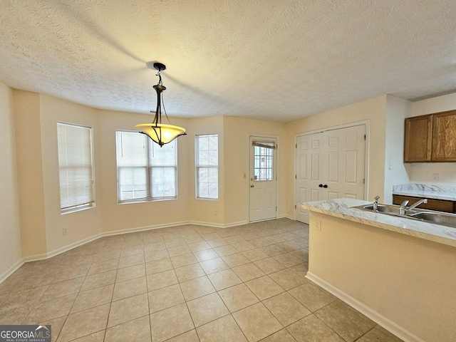 kitchen with pendant lighting, sink, a textured ceiling, and light tile patterned flooring