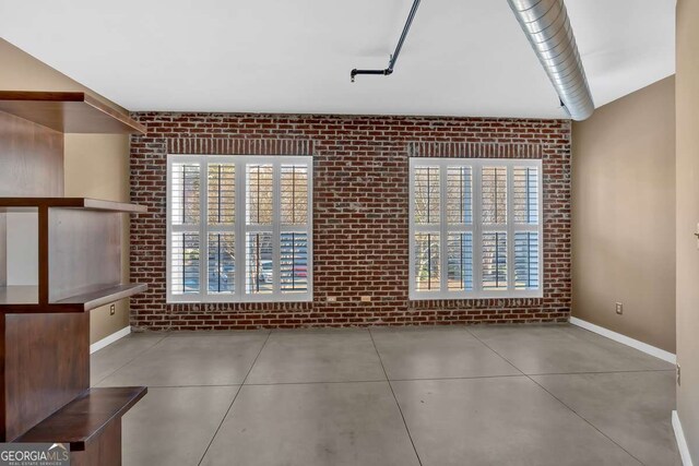 unfurnished room featuring brick wall and concrete flooring