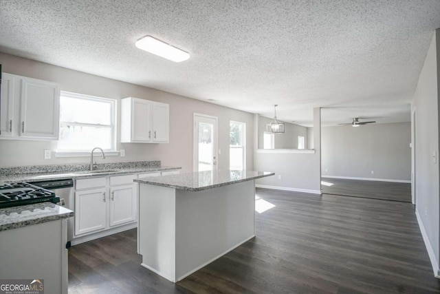 kitchen with decorative light fixtures, white cabinetry, a kitchen island, and sink