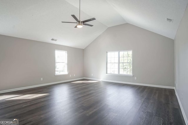 unfurnished room with dark hardwood / wood-style floors, vaulted ceiling, a wealth of natural light, and ceiling fan