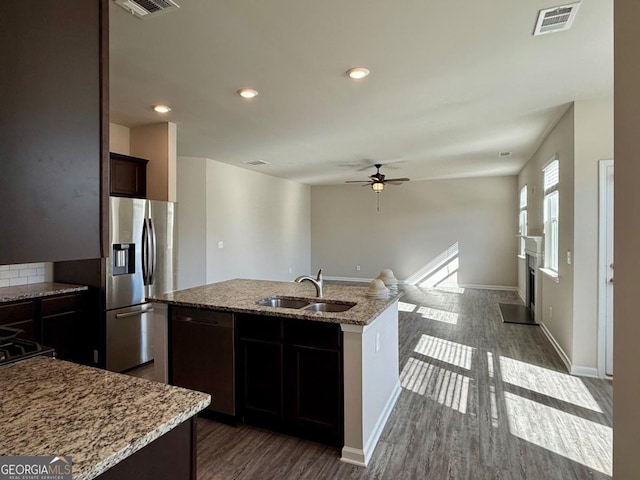 kitchen featuring ceiling fan, a kitchen island with sink, sink, dishwasher, and dark hardwood / wood-style floors