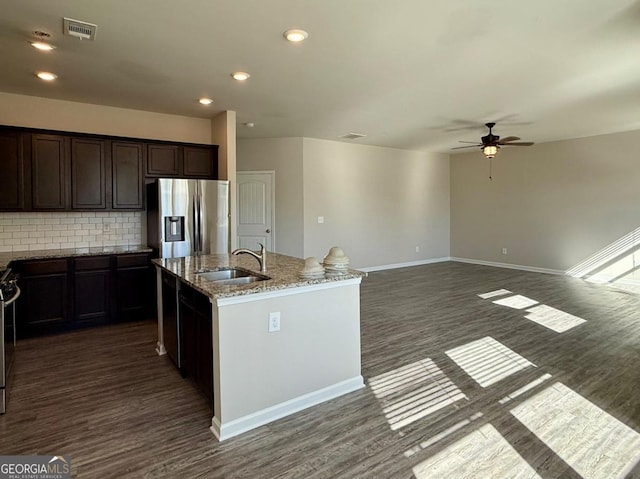 kitchen with sink, dark wood-type flooring, stainless steel appliances, an island with sink, and decorative backsplash