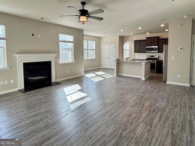 unfurnished living room featuring ceiling fan and dark wood-type flooring